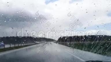 雨天从高速公路上行驶的汽车挡风玻璃上滴下的雨滴。